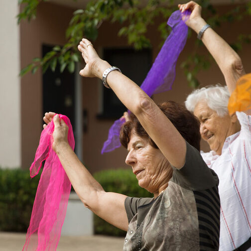 Ältere Frauen bewegen sich mit bunten Tüchern in der Hand.