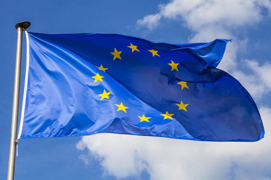 Europaflagge weht an einem Fahnenmast vor blauem Himmel.