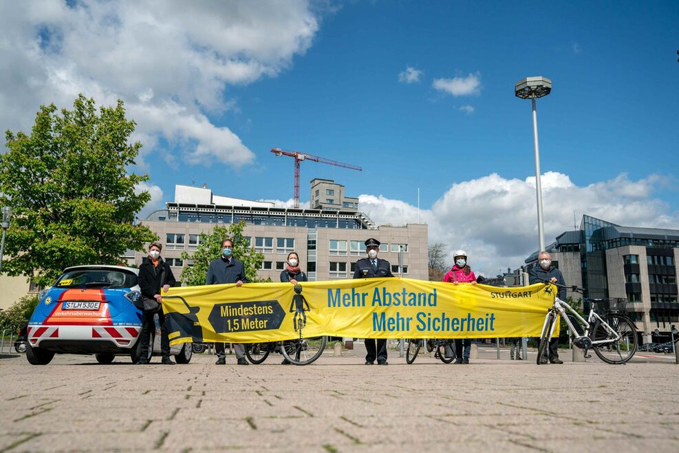 Sechs Menschen stehen auf einem Platz und präsentieren einen Banner mit der Aufschrift "Mehr Abstand, mehr Sicherheit".