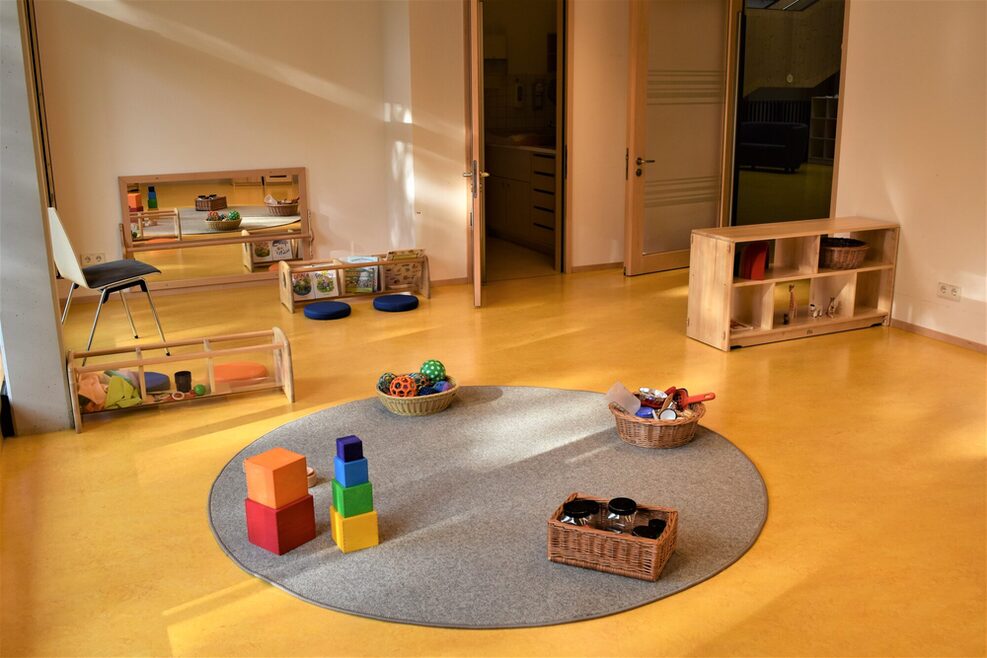 Der Kleinkindbereich ist mit verschiedenen Spielsachen ausgestattet, z.B. Greifbälle, Greifringe und Bauklötzchen.