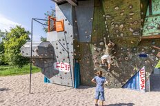 Zwei Kinder klettern an einer Boulder-Wand, die am Spielplatz Schelmenäcker angebracht ist.