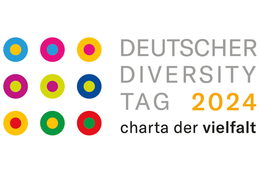 Das Logo "Diversity Tag 2024 charta der Vielfalt" zeigt diesen Text und einige verschiedenfarbige Punkte, die die Unterschiede der Menschen symbolisieren.