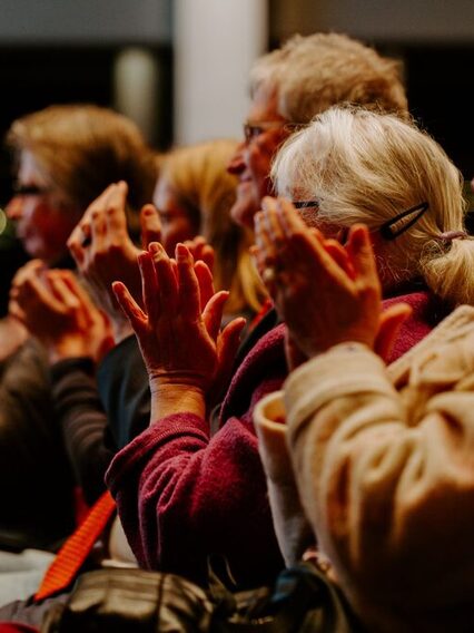 Mehrere Menschen sitzen in eier Reihe und applaudieren.