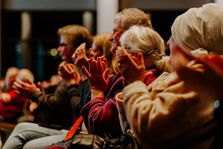 Mehrere Menschen sitzen in eier Reihe und applaudieren.