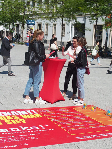 Eine Frau berät zwei Passantinnen in der Fußgängerzone über Ehrenamt.