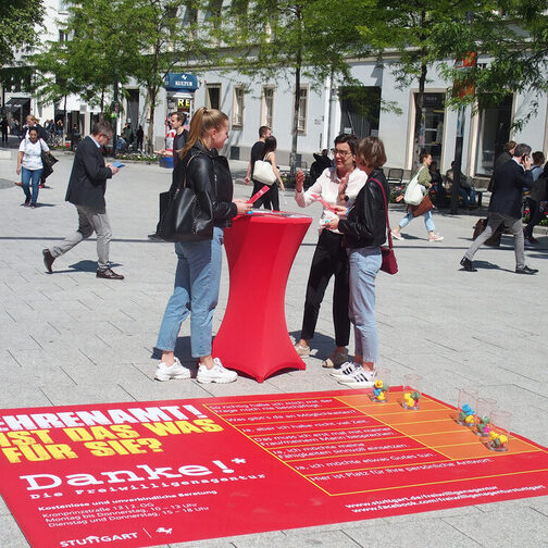 Eine Frau berät zwei Passantinnen in der Fußgängerzone über Ehrenamt.