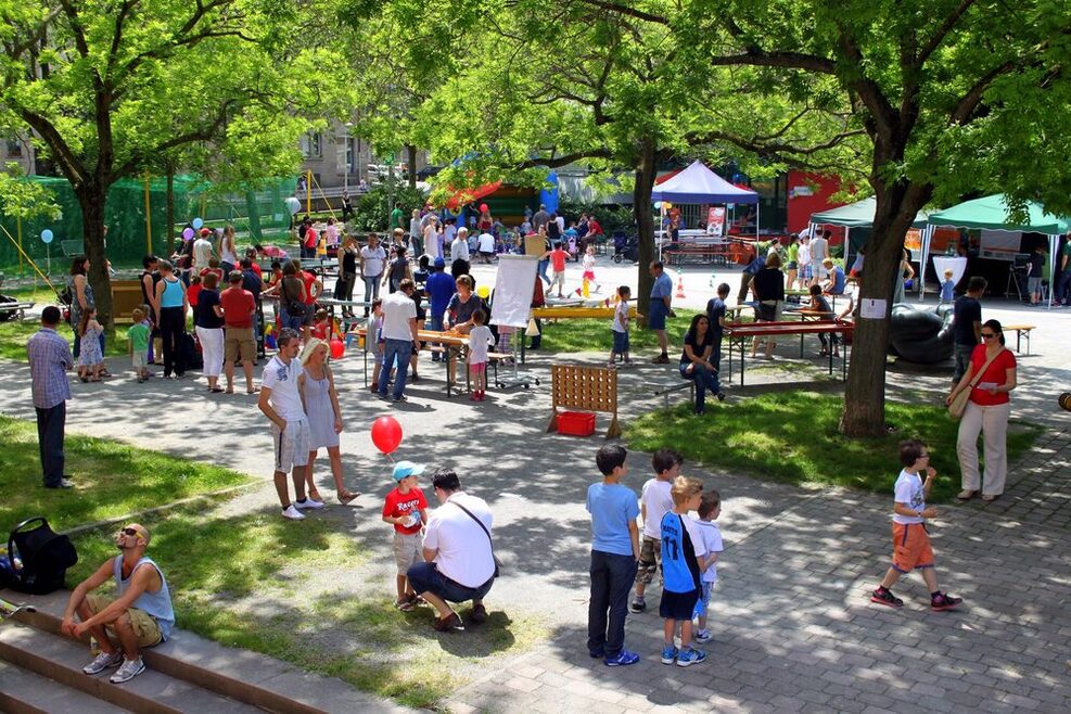 Erwachsene und Kinder beim Bürgerfest auf einem Platz in sommerlicher Atmosphäre.