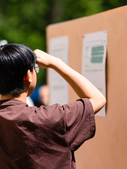 Zwei Menschen schauen auf eine Pin-Wand, auf der Ergebnisse des Bürgerrats Klima stehen.
