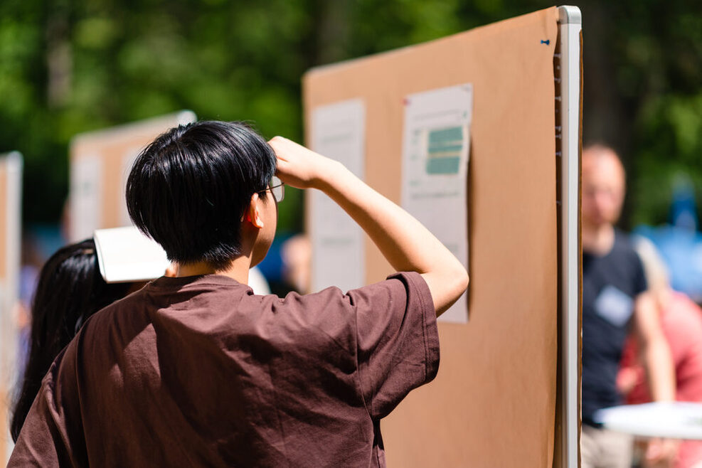 Zwei Menschen schauen auf eine Pin-Wand, auf der Ergebnisse des Bürgerrats Klima stehen.