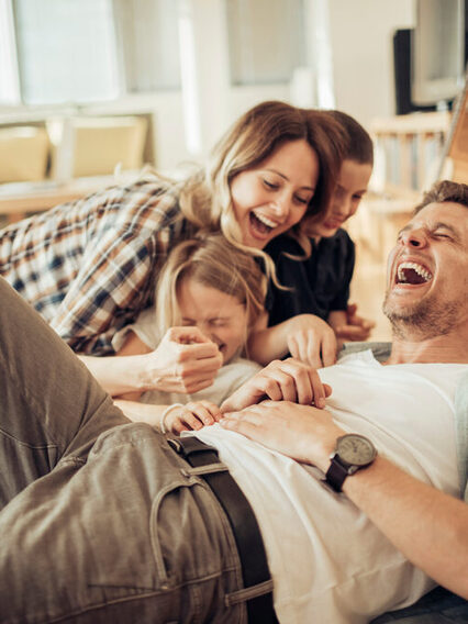 Junge Familie lacht im Wohnzimmer.