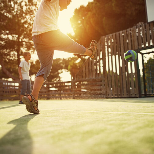 Kinder beim Fußballspielen auf dem Bolzplatz.