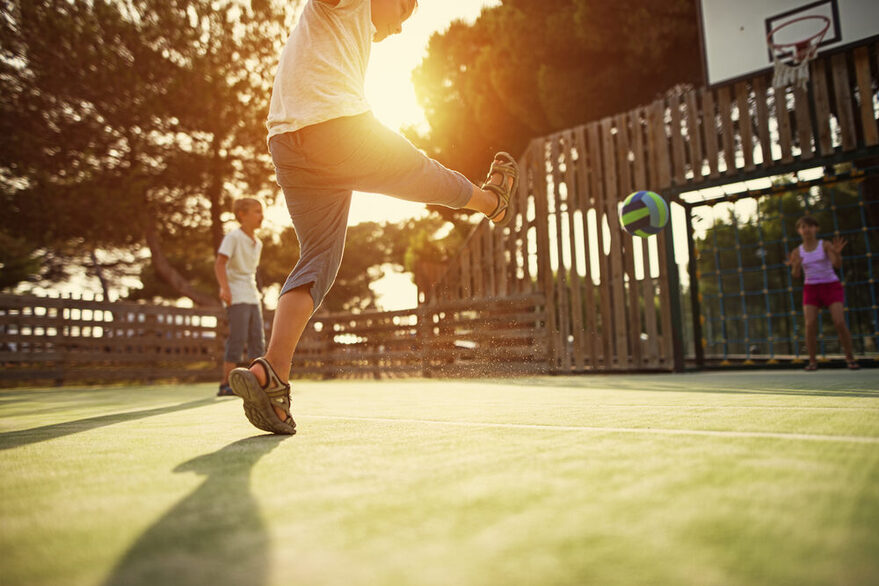 Kinder beim Fußballspielen auf dem Bolzplatz.