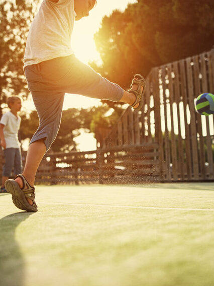 Kinder beim Fußballspielen auf dem Bolzplatz.