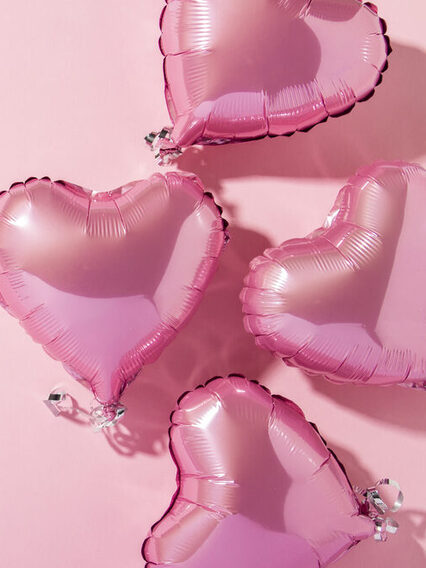 Mehrere Herzluftballons auf pinkem Hintergrund.