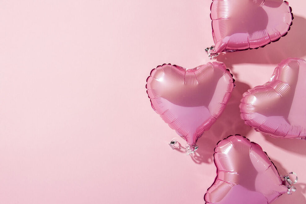 Mehrere Herzluftballons auf pinkem Hintergrund.