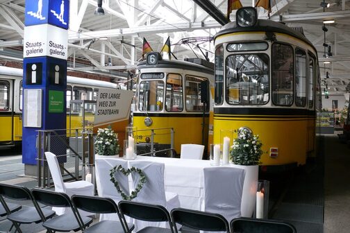 Hochzeitsdekoration, Stühle und Tisch vor historischen Straßenbahnen.