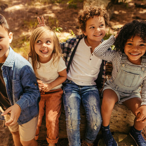 Vier Kinder machen Faxen in einem Wald.