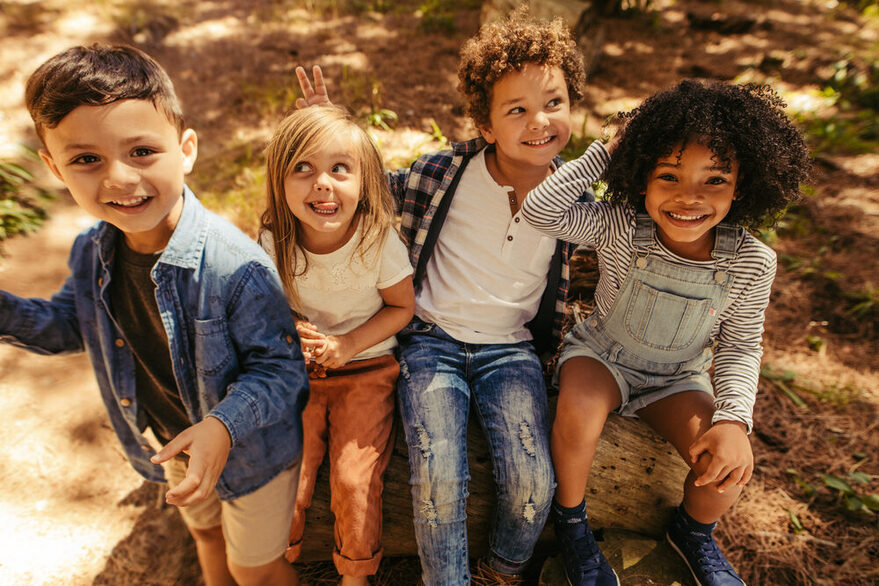 Vier Kinder machen Faxen in einem Wald.