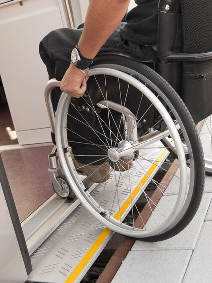 Zu sehen ist ein/e Rollstuhlfahrer*in, der/die eine S-Bahn über eine ausfahrbare Rampe betritt.