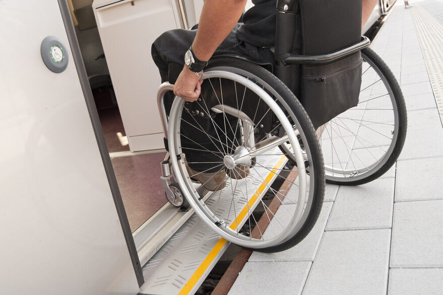 Zu sehen ist ein/e Rollstuhlfahrer*in, der/die eine S-Bahn über eine ausfahrbare Rampe betritt.