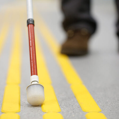 Close-up of a blind person's cane using the guidance system on the asphalt for orientation