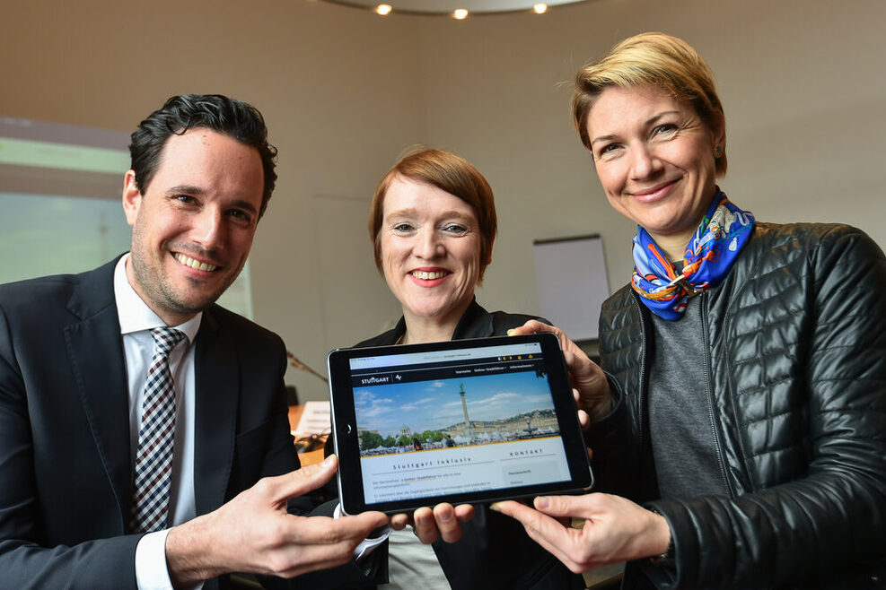 Erster Bürgermeister Dr. Fabian Mayer, die Beauftragte für Menschen mit Behinderung Simone Fischer und Sozialbürgermeisterin Dr. Alexandra Sußmann halten gemeinsam ein Tablet in der Hand.