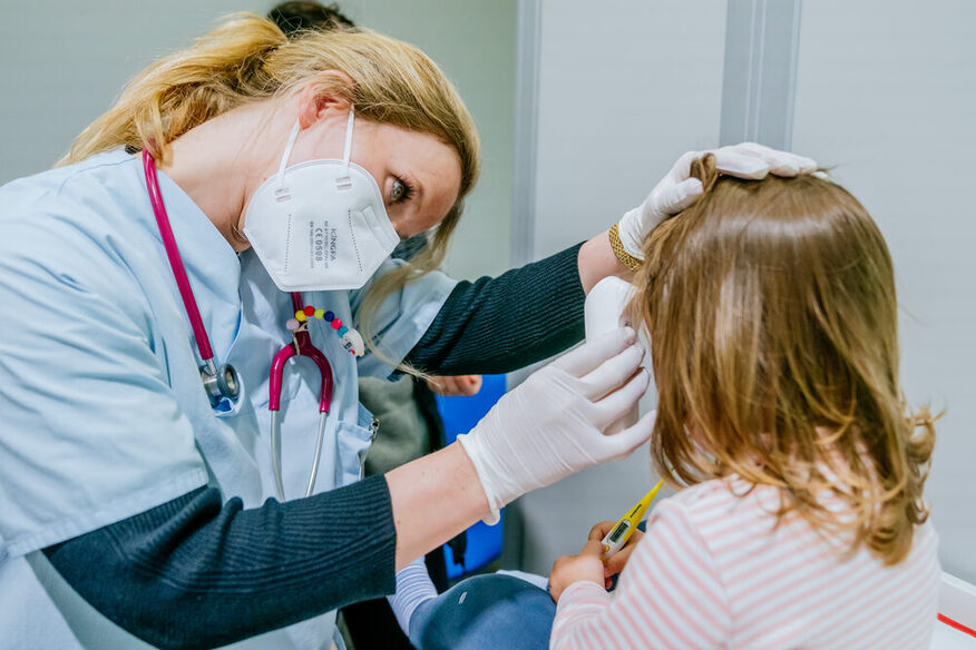 Eine Ärztin mit Maske untersucht ein Kind.