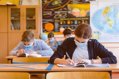 Kinder sitzen in einer Klasse und schreiben in ihr Schulheft