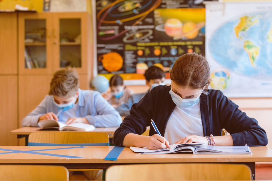 Kinder sitzen in einer Schulklasse und schreiben in ihr Schulheft