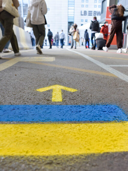 Wegweiser am Hauptbahnhof Stuttgart für Menschen aus Ukraine, zwei Farbstreifen in blau und gelb mit einem Pfeil