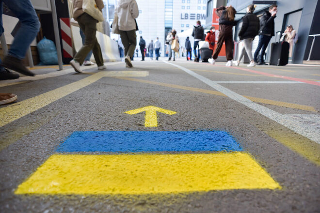 Wegweiser am Hauptbahnhof Stuttgart für Menschen aus Ukraine, zwei Farbstreifen in blau und gelb mit einem Pfeil