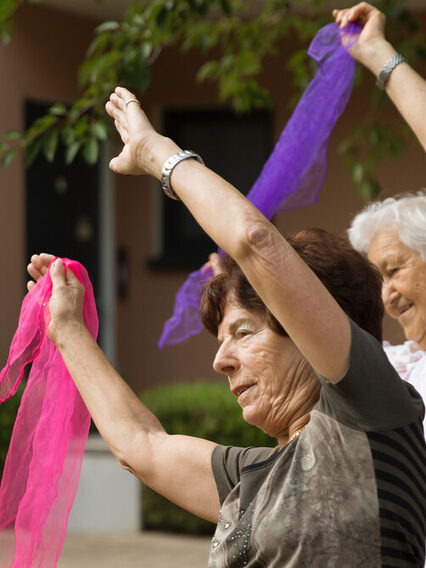 Ältere Frauen bewegen sich mit bunten Tüchern in der Hand.