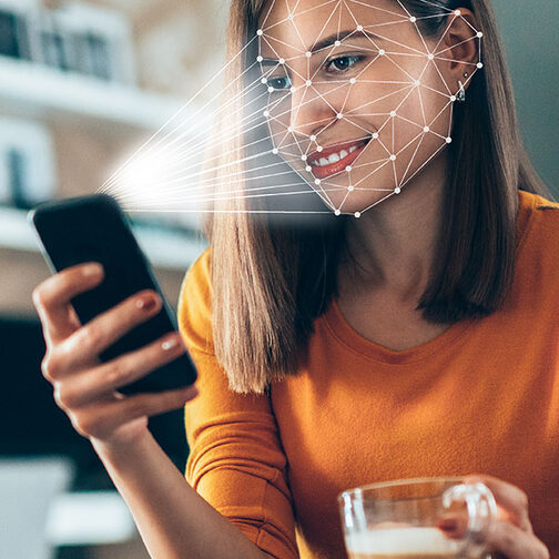Woman with smartphone in hand uses facial recognition.