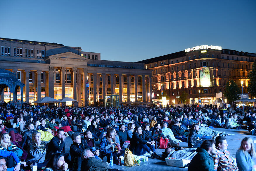 Zuschauer sitzen auf dem Schlossplatz beim Open Air Kino.