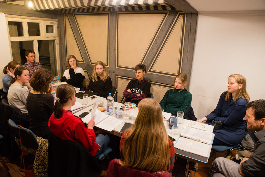 Mehrere junge Menschen sitzen an einem Tisch und unterhalten sich.