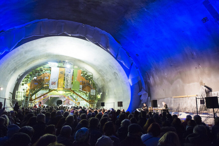 Mehrere Menschen stehen in einem Tunnel, in dem eine Bühne aufgebaut ist.