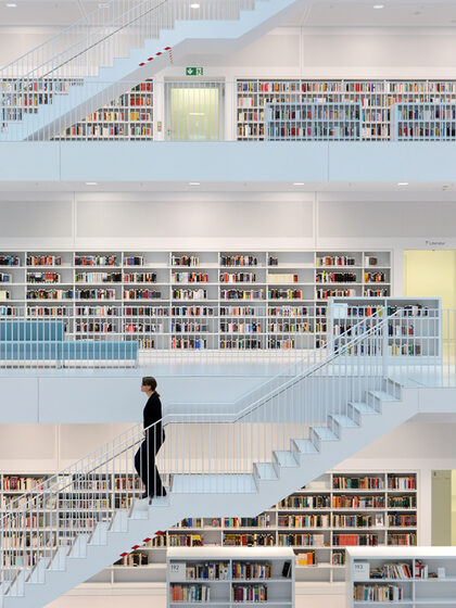 Ein Frau geht in einer Bücherei eine Treppe hinab.