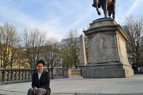Nadine Seidu, die Leiterin der Koordininierungsstelle Erinnerungskultur am Karlsplatz vor einer Reiterstatur