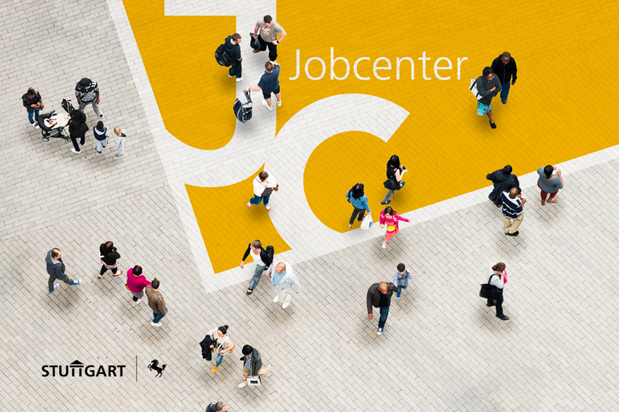 Viele Menschen gehen über einen gepflasterten Platz, das Bild ist aus der Vogelperspektive zu sehen. Auf dem Pflasterboden ist die Wortmarke des Jobcenters Stuttgart zu erkennen.