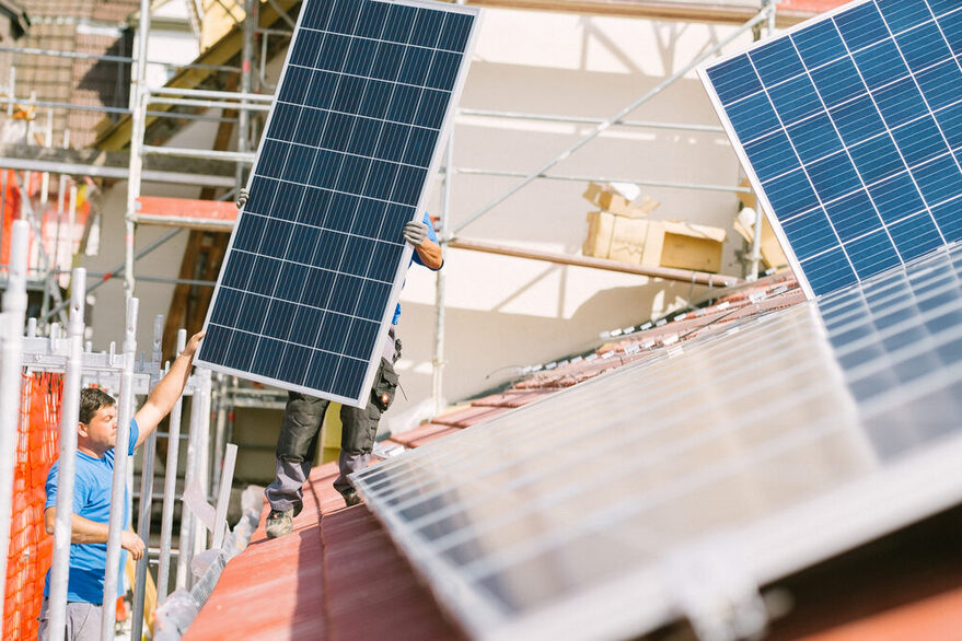 Zwei Männer montieren Solarpanelen auf ein Dach.