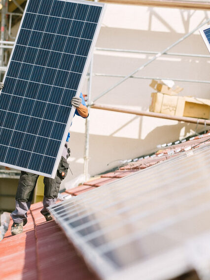 Zwei Männer montieren Solarpanelen auf ein Dach.