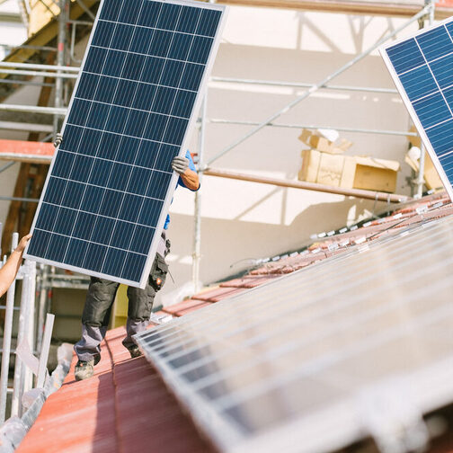 Zwei Männer montieren Solarpanelen auf ein Dach.