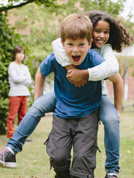 Schulkinder haben Spaß: Sie laufen Huckepack auf dem Schulhof.