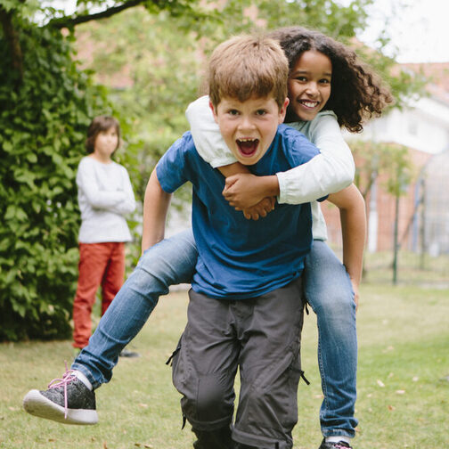 Schulkinder haben Spaß: Sie laufen Huckepack auf dem Schulhof.