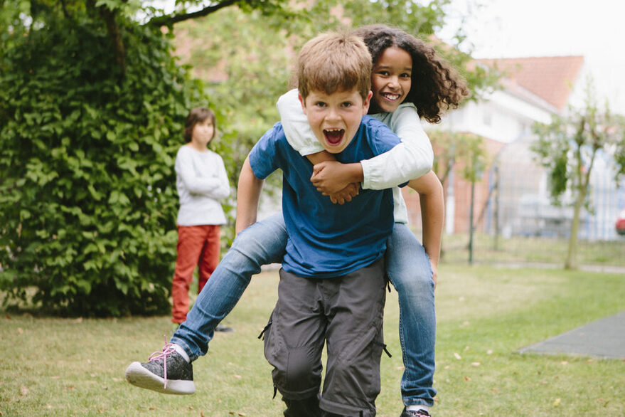 Schulkinder haben Spaß: Sie laufen Huckepack auf dem Schulhof.