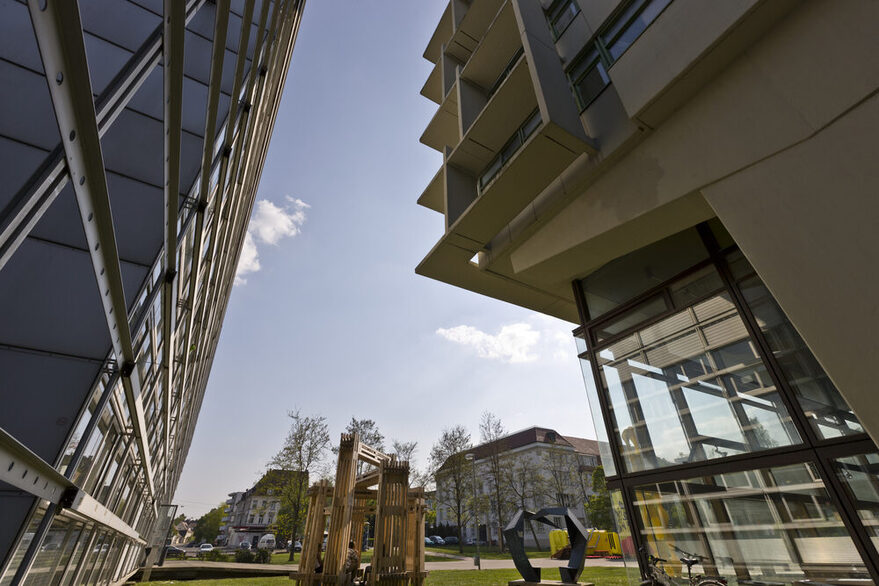 Blick durch zwei Gebäude auf einen Campus, im Hintergrund stehen weitere Gebäude.