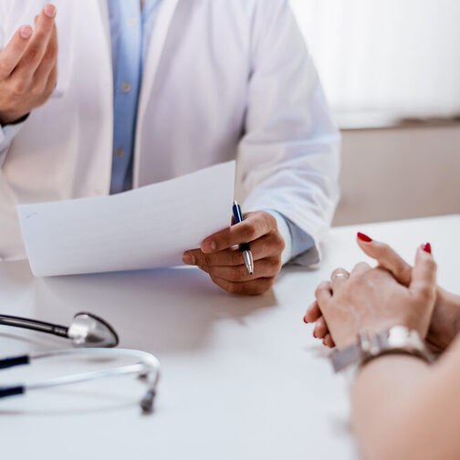 Arzt hält Antragsformular bei der Beratung eines Patienten