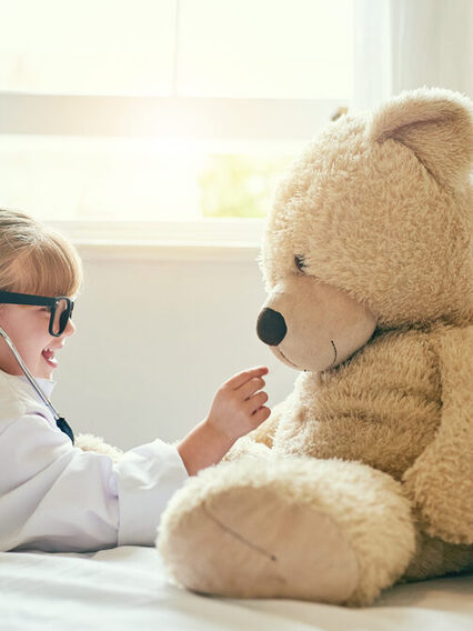 Als Ärztin verkleidetes Mädchen untersucht Teddybär.