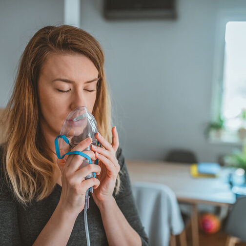 Junge Frau mit Inhalator zuhause.