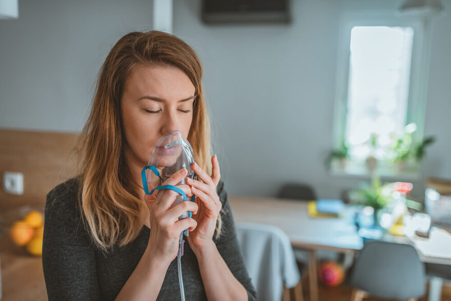 Junge Frau mit Inhalator zuhause.